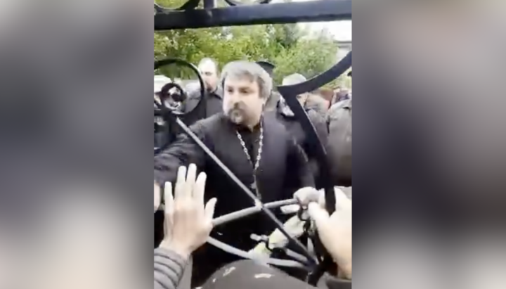 Клирик ПЦУ взламывает калитку на территорию храма УПЦ в Заставне. Фото: СПЖ