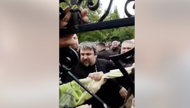 <р>Κληρικός της ΠЦУ σπάει την πόρτα στην είσοδο του ναού της УПЦ στη Ζαστάβνα. Φωτογραφία: СПЖ</р>